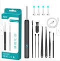 Black and white wireless otoscope ear cleaner with camera, LED light, and spoon heads on a table.