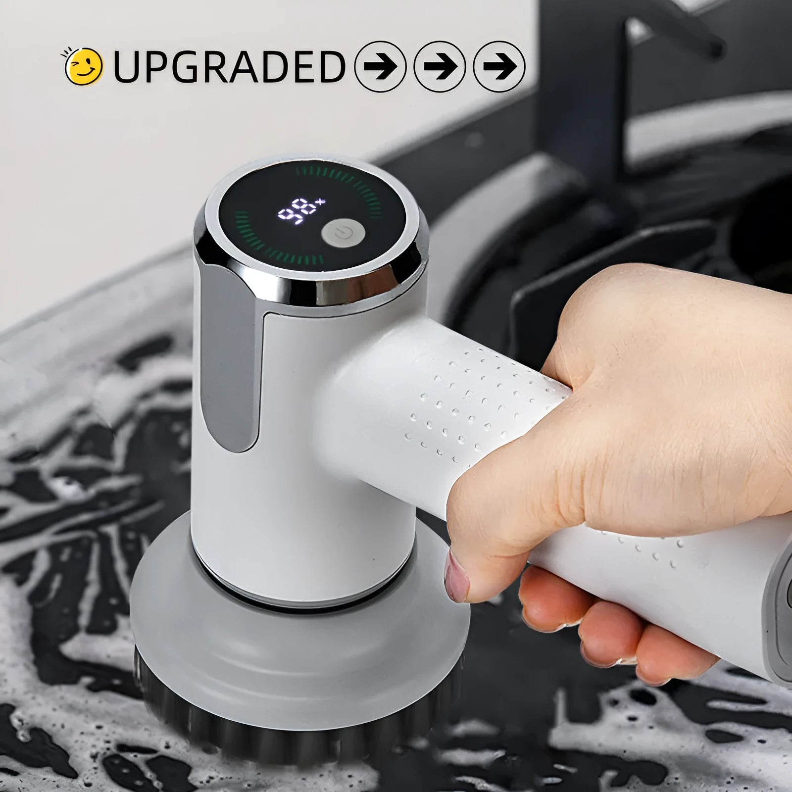 White wireless electric cleaning brush with display, Type-C port, and interchangeable brush heads on a kitchen sink