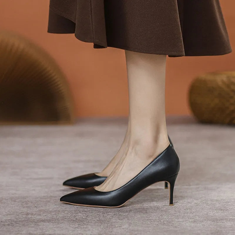 Black pointed-toe high heel shoes with a stiletto heel on a plain background