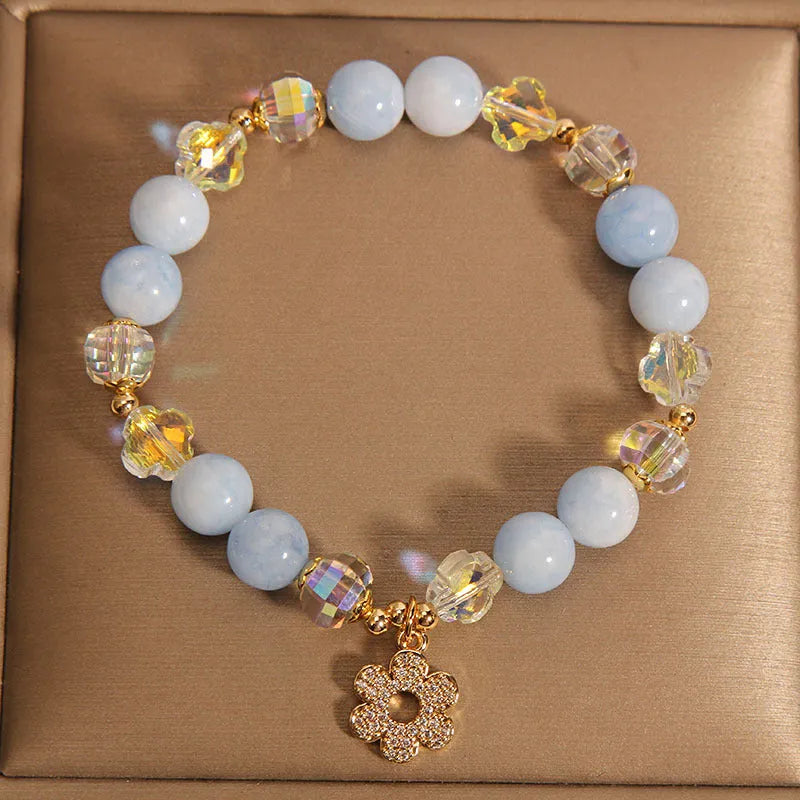 Aquamarine crystal and pearl bracelet with four-leaf clover charm on wrist.