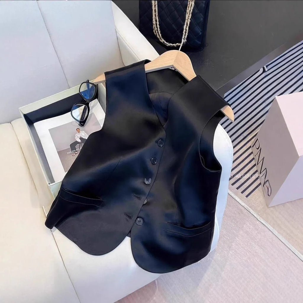 Black satin vest with sleeveless design and splicing details, shown on hanger