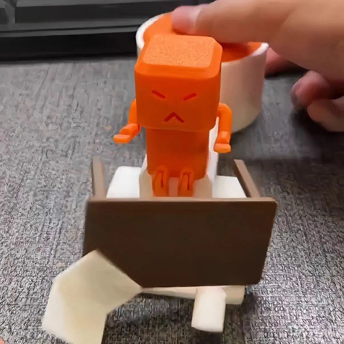Orange plastic table-turning decompression toy measuring 16x6x7cm on wooden desk