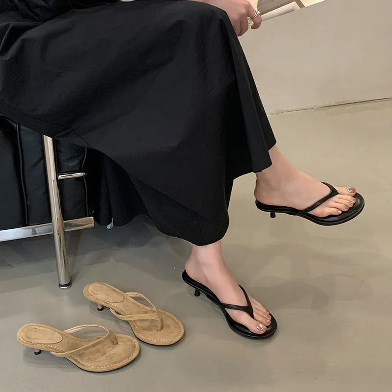 Women's black rubber stiletto flip-flops with round toe and flat head cap on a plain background.