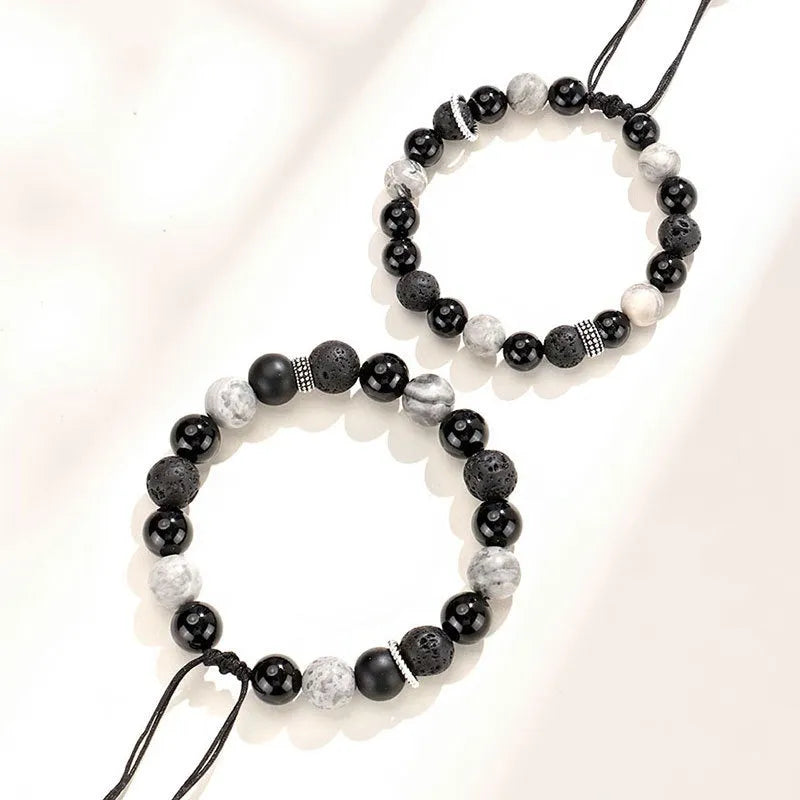 Black agate map stone volcanic rock bracelet with diamond-shaped beads on a wrist.