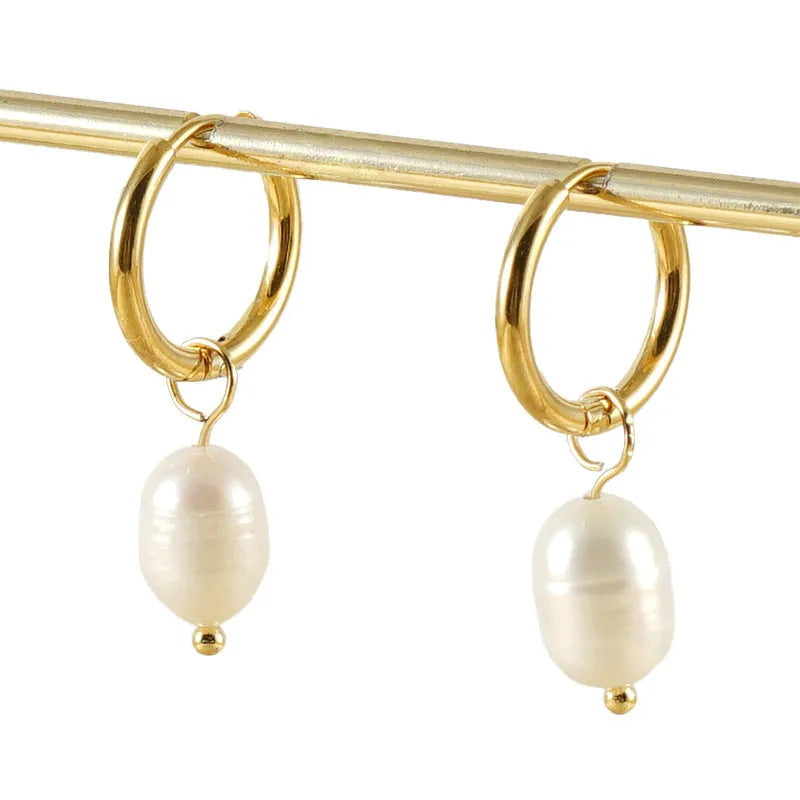 Gold geometric earrings with freshwater pearl accent on stainless steel background