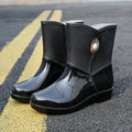 Women's purple PVC rain boots with a middle tube height and non-slip sole on a wet surface.
