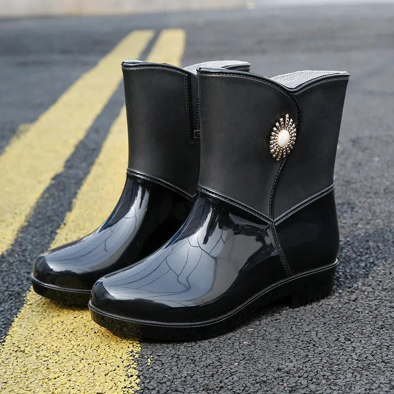 Women's purple PVC rain boots with a middle tube height and non-slip sole on a wet surface.