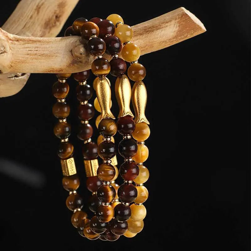 Yellow tiger eye bracelet with small fish bead charm on woman's wrist