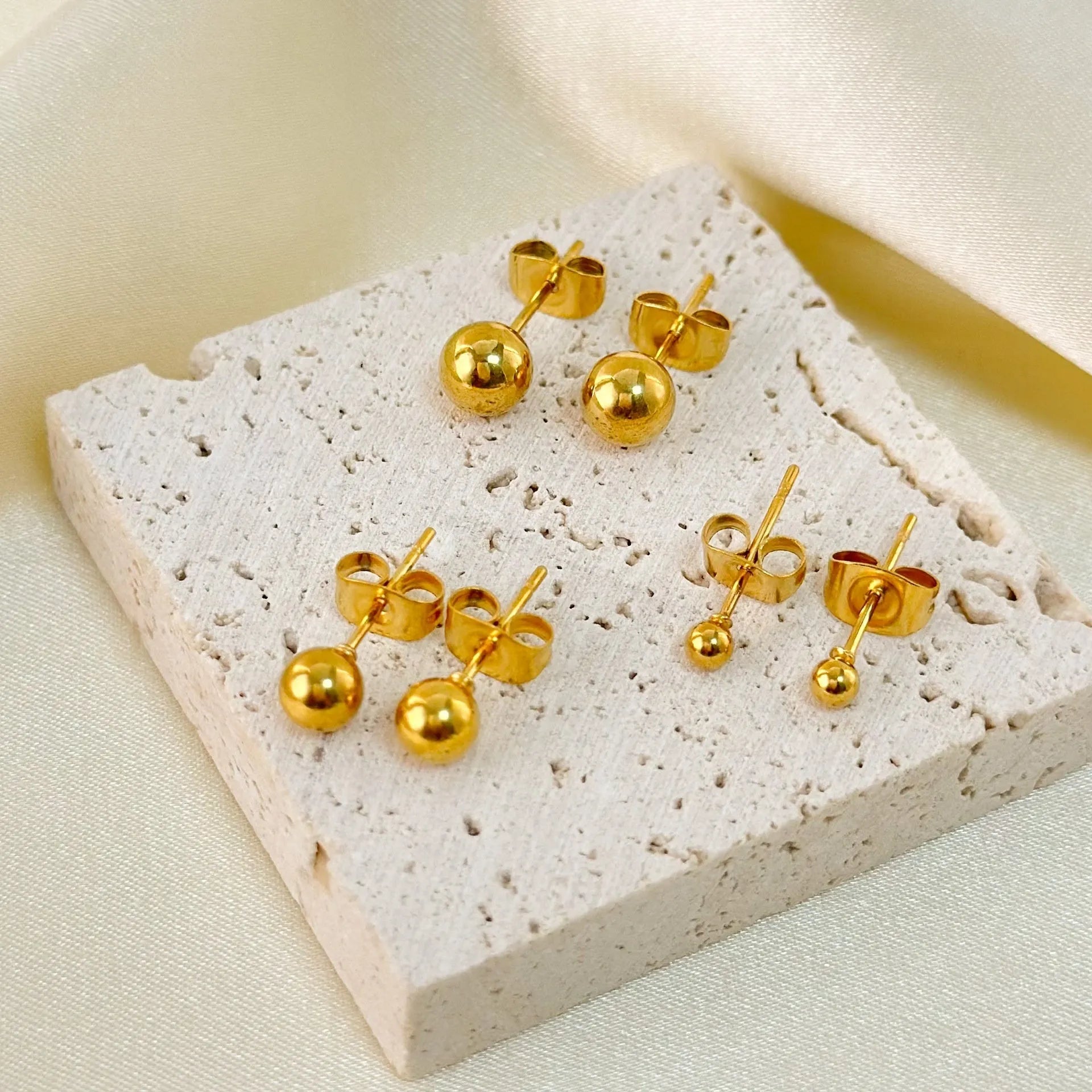 Stainless steel ball stud earrings with round geometric design in gold or silver finish, showing front and side views