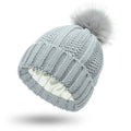 Women's white skull knit beanie with faux fur pom pom, showing satin paisley lining.