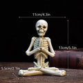 Hand-painted resin yoga pose skull skeleton ornament measuring 10.5-11cm wide on wooden desktop