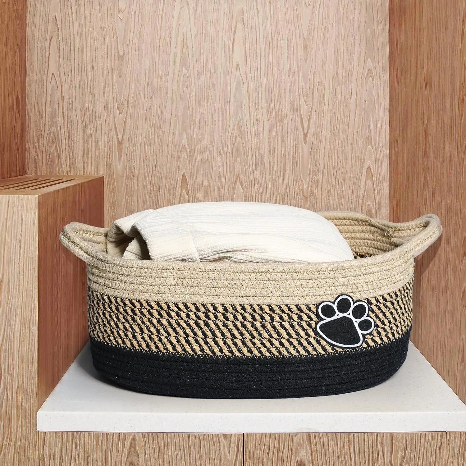 Small woven cotton rope storage basket with wooden handle in light beige, measuring 34x26x15cm, on a shelf with toys