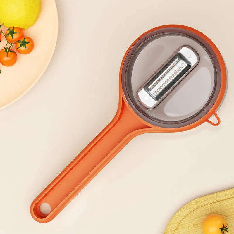 Light green kitchen peeler with attached storage bucket for catching fruit and vegetable peelings