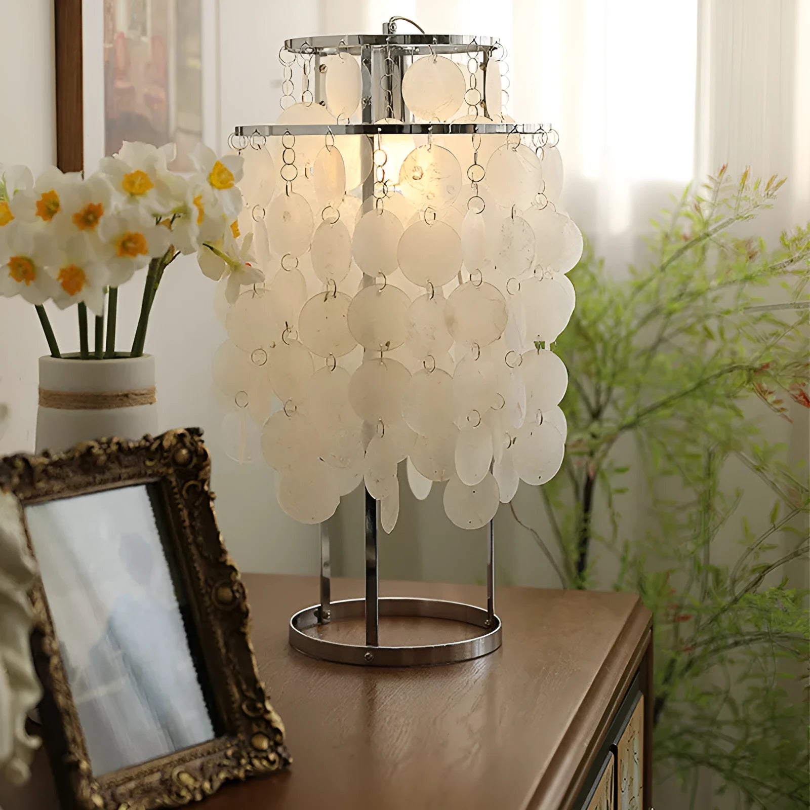 Modern shell-shaped bedside table lamp in a chrome finish on a wooden surface.