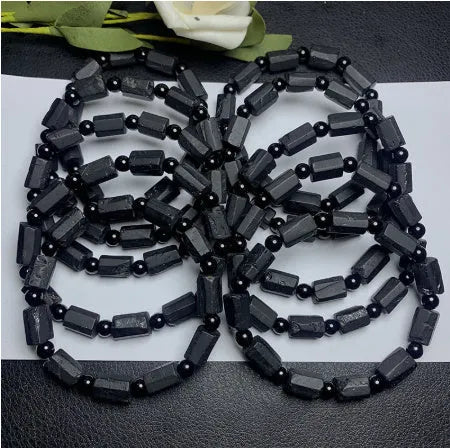 Unisex black tourmaline rough stone bracelet on wrist, showing natural texture and 10mm band width.