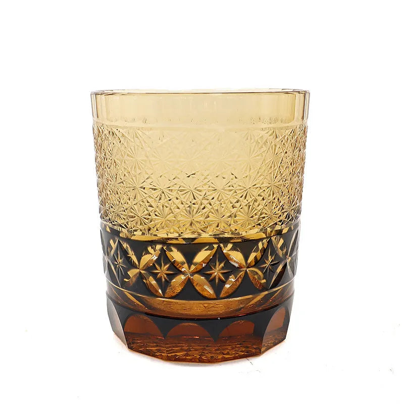 Hand carved Japanese style crystal whiskey glass in amber colour on a dark surface