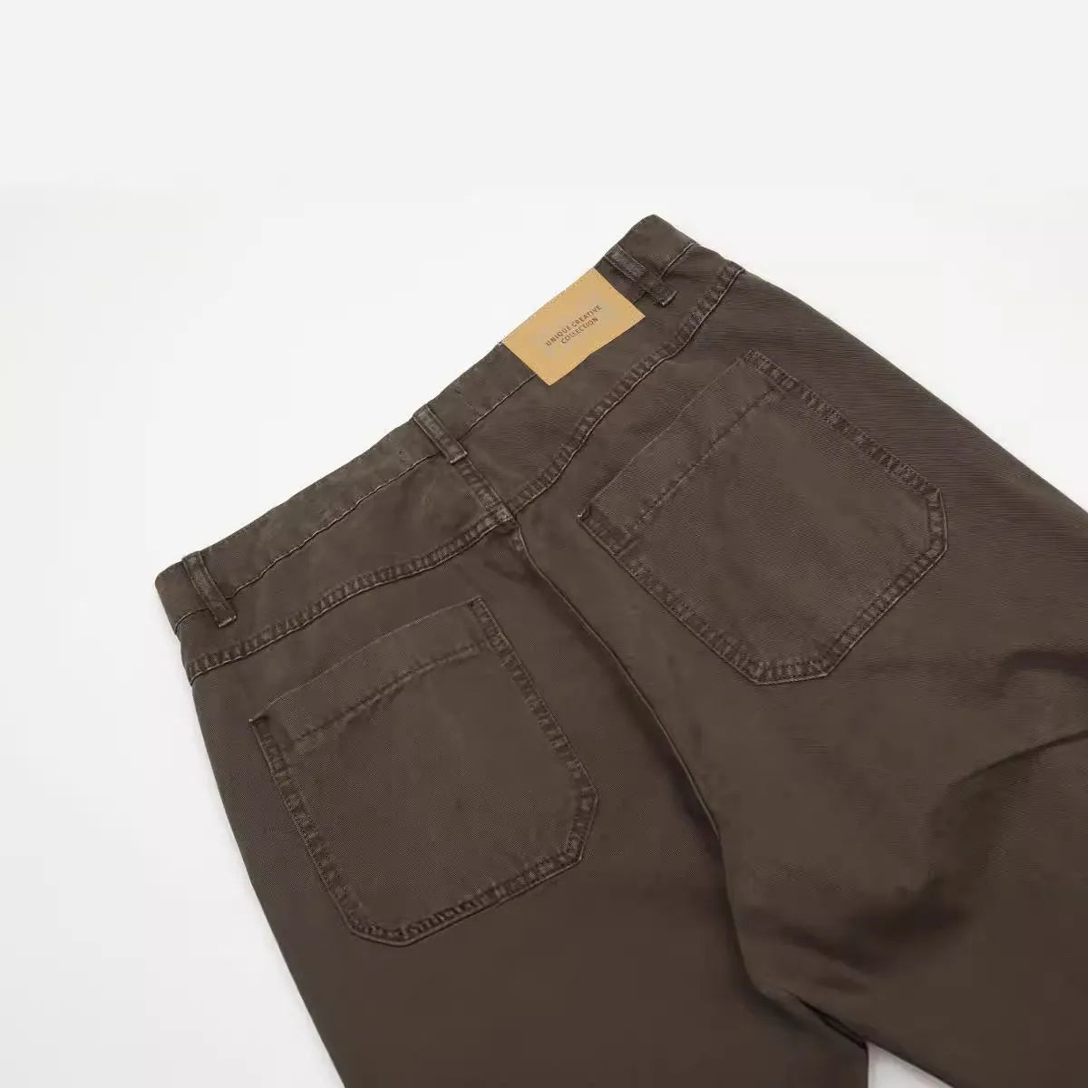 Men's brown straight-leg trousers with high waist and non-ironing cotton fabric on a hanger