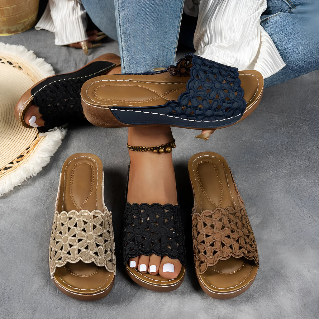 Women's black wedge beach slippers with flower cutout design and open fish mouth toe.