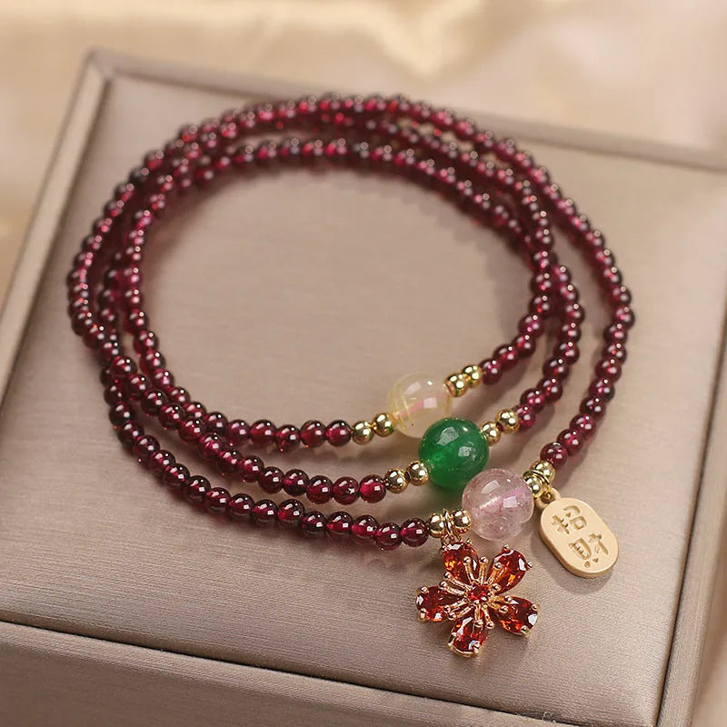 Women's crystal bracelet with pomegranate red cherry blossom beads and sequin details on a simple band.