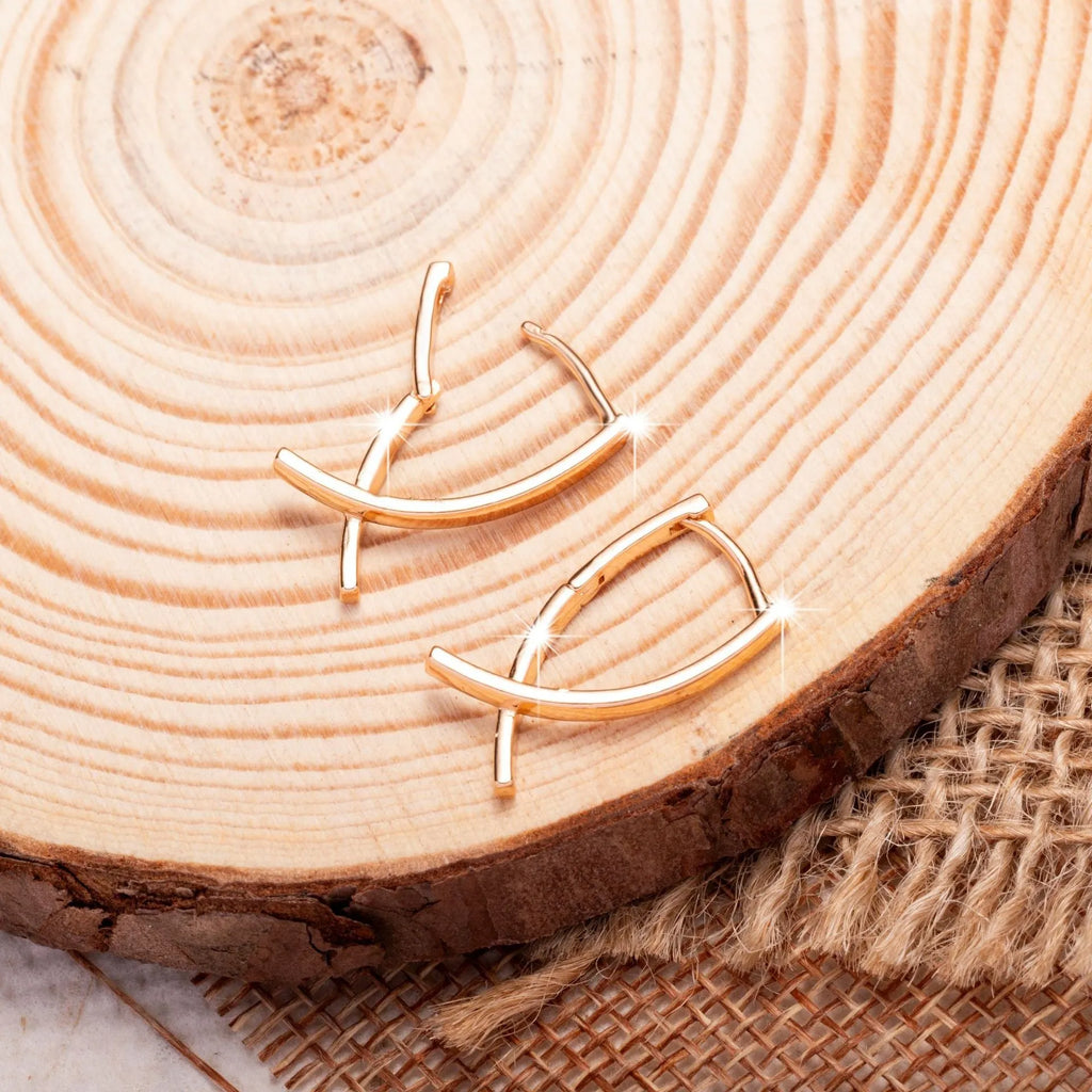 Pair of rose gold cross-shaped earrings on a plain background, showing pierced post design.