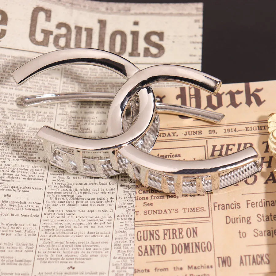 Assortment of silver metal hair claw barrettes in various shapes including waves, bows, and crosses.