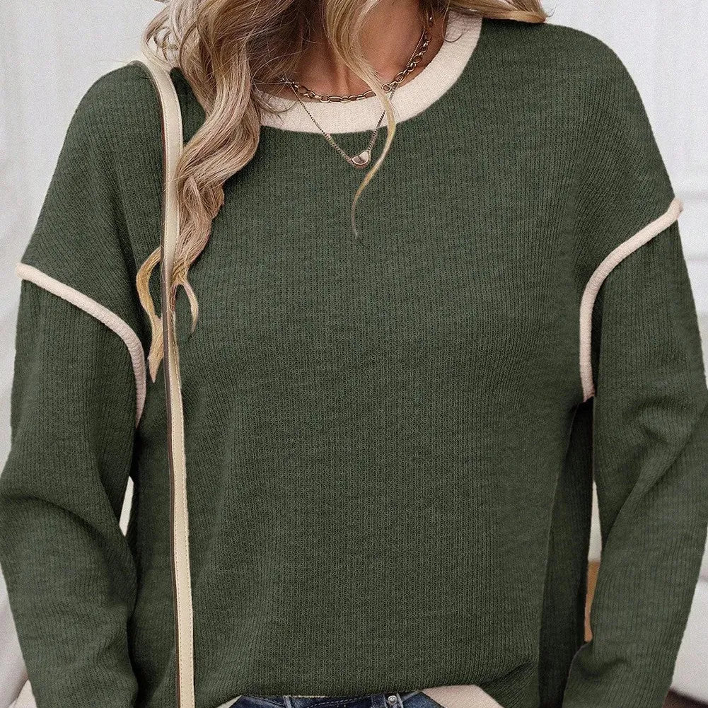 Beige loose drop shoulder knit top with green four-leaf clover design and contrast trim on neckline.