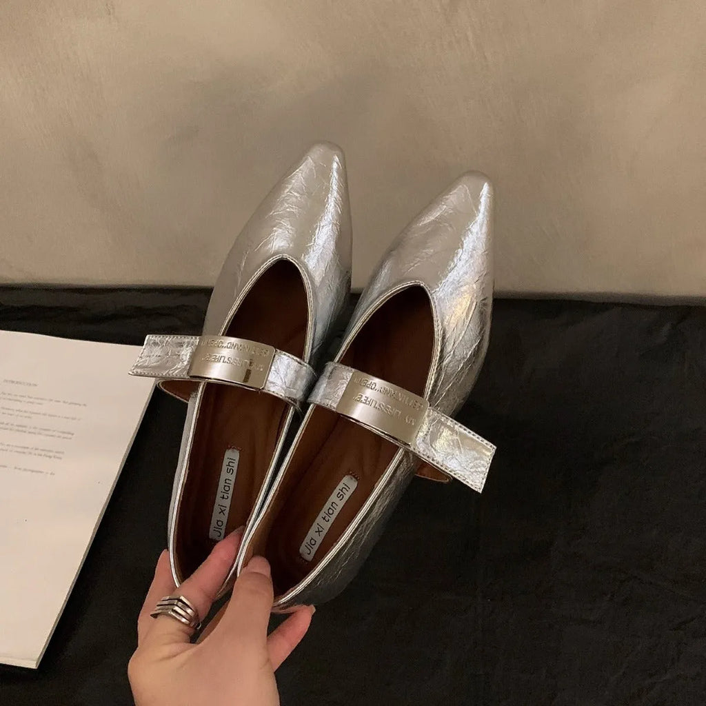 Women's black pointed toe Mary Jane shoes with a silver buckle and a low flat heel.