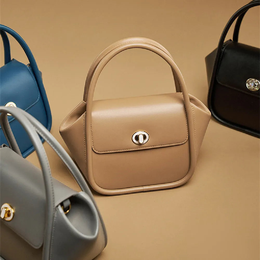 Leather tote cross-body wing bag in soft cow leather with latch closure and wing shape design.