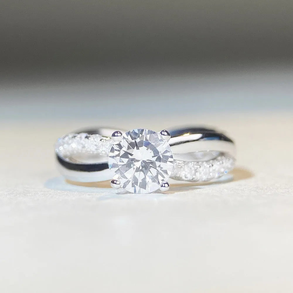 Geometric silver moissanite ring with twisted arm design and four-claw setting, shown in white diamond colour.