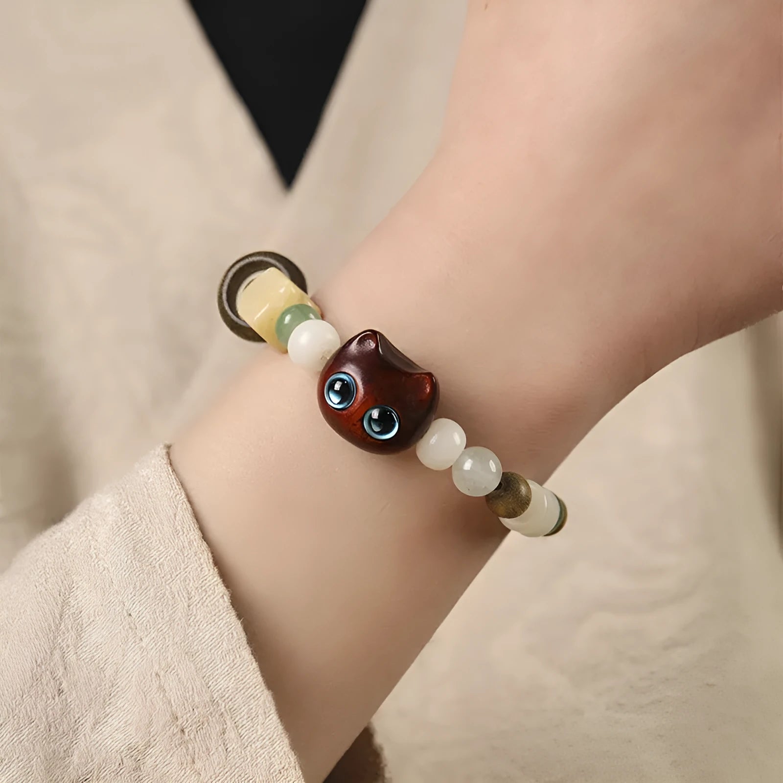 Hand-woven beaded bracelet with a cat's paw charm, multi-treasure cube, and mix of jade and wood beads.