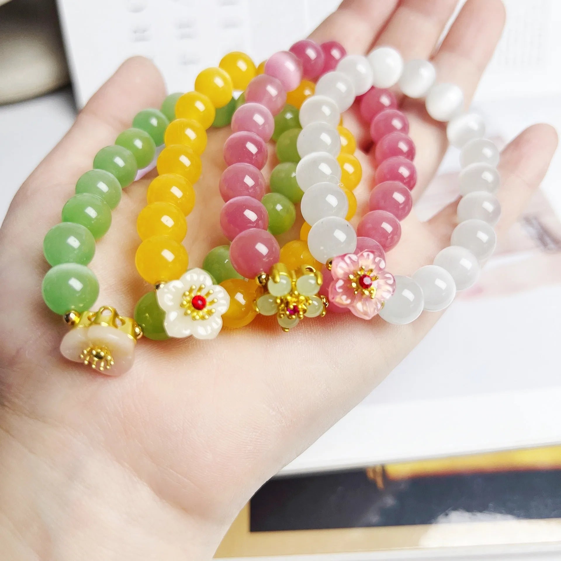 Handmade glass bead bracelet with floral designs in green, pink, white, or yellow colours