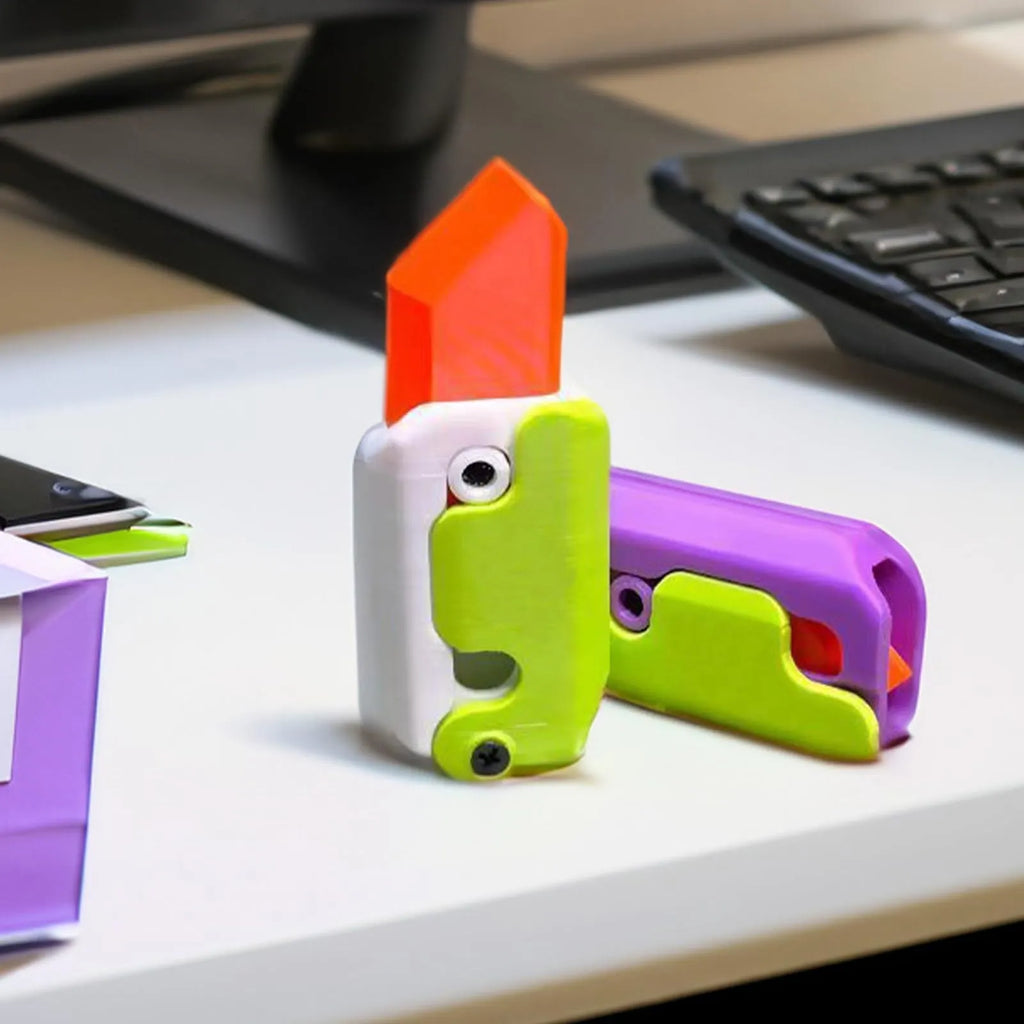 3D printed orange and green carrot-shaped gravity flick knife fidget toy on a white background.