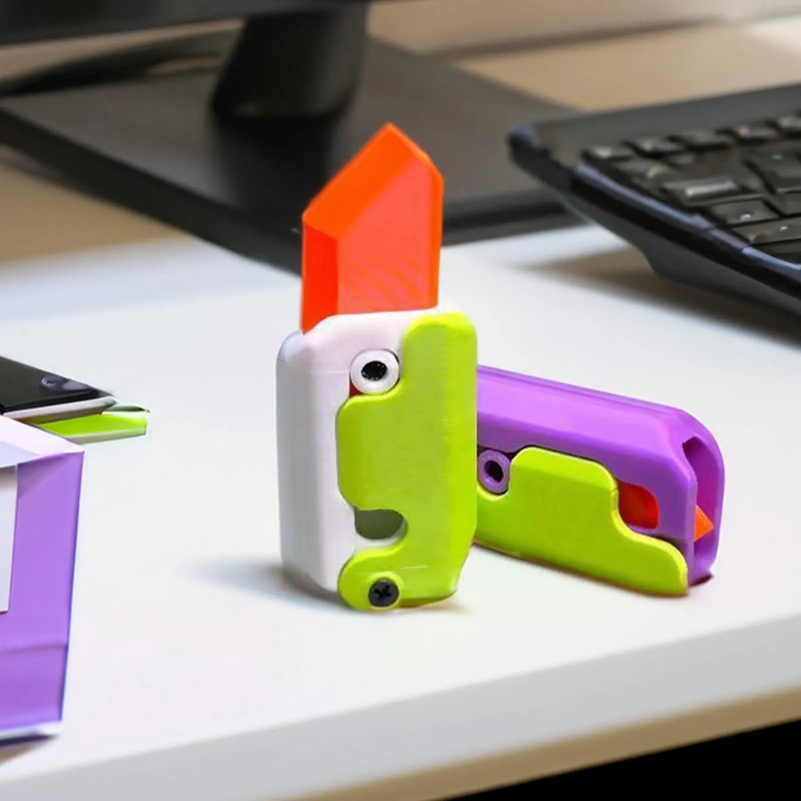 3D printed orange and green carrot-shaped gravity flick knife fidget toy on a white background.