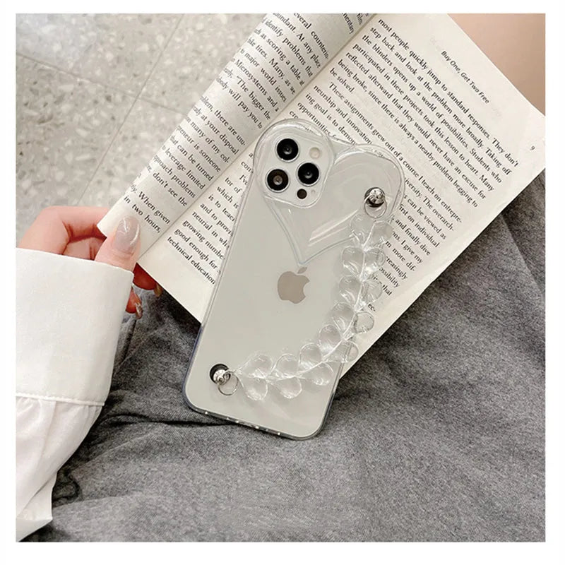 Transparent iPhone case with a soft TPU build and an integrated love heart chain, shown on a phone.