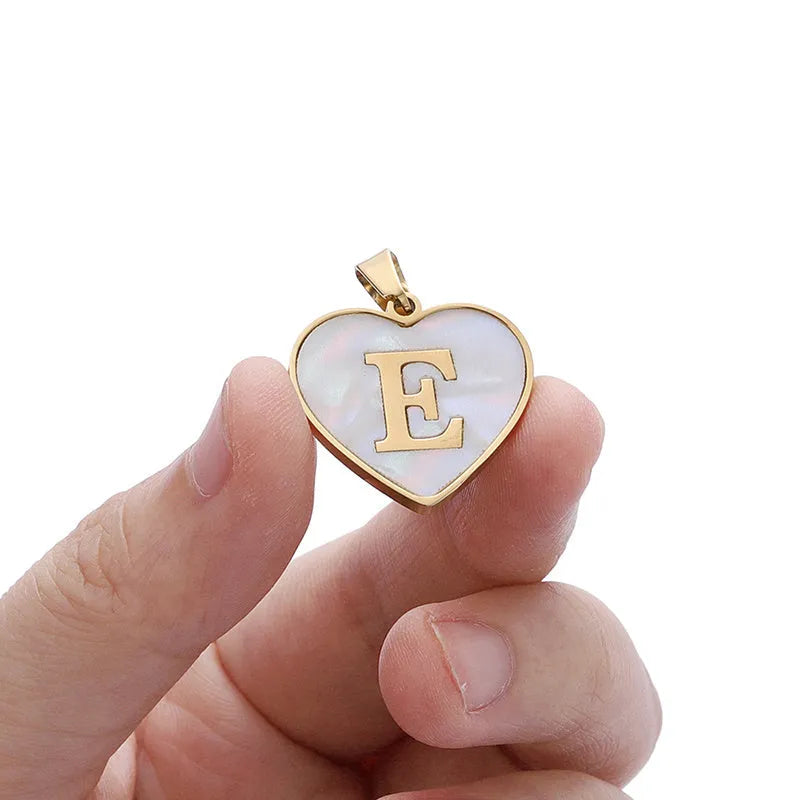 Gold-plated heart-shaped white shell initial necklace on a model, showing the adjustable clavicle chain.