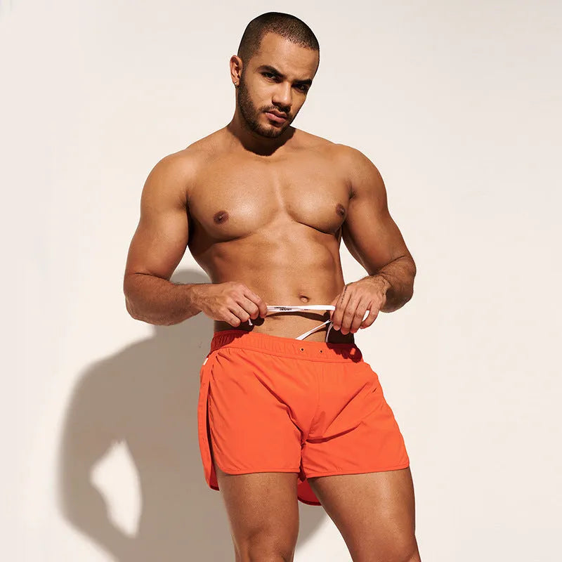Men's loose beach surfing shorts in orange, fluorescent green, or black with elastic waistband and micro-elastic fabric