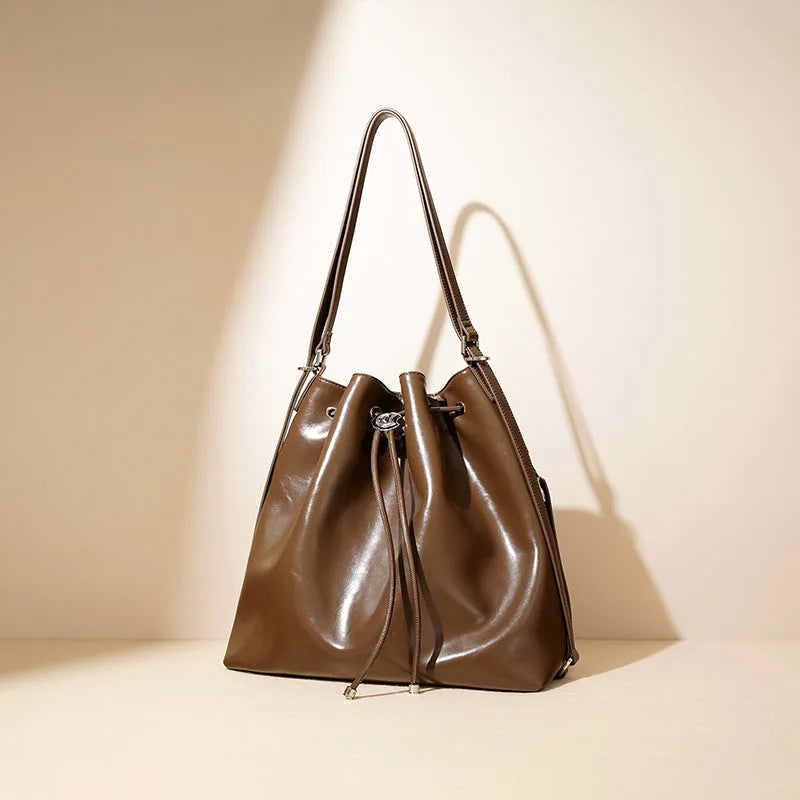 Genuine leather one-shoulder bucket bag in brown showing interior file compartment and zippered pockets