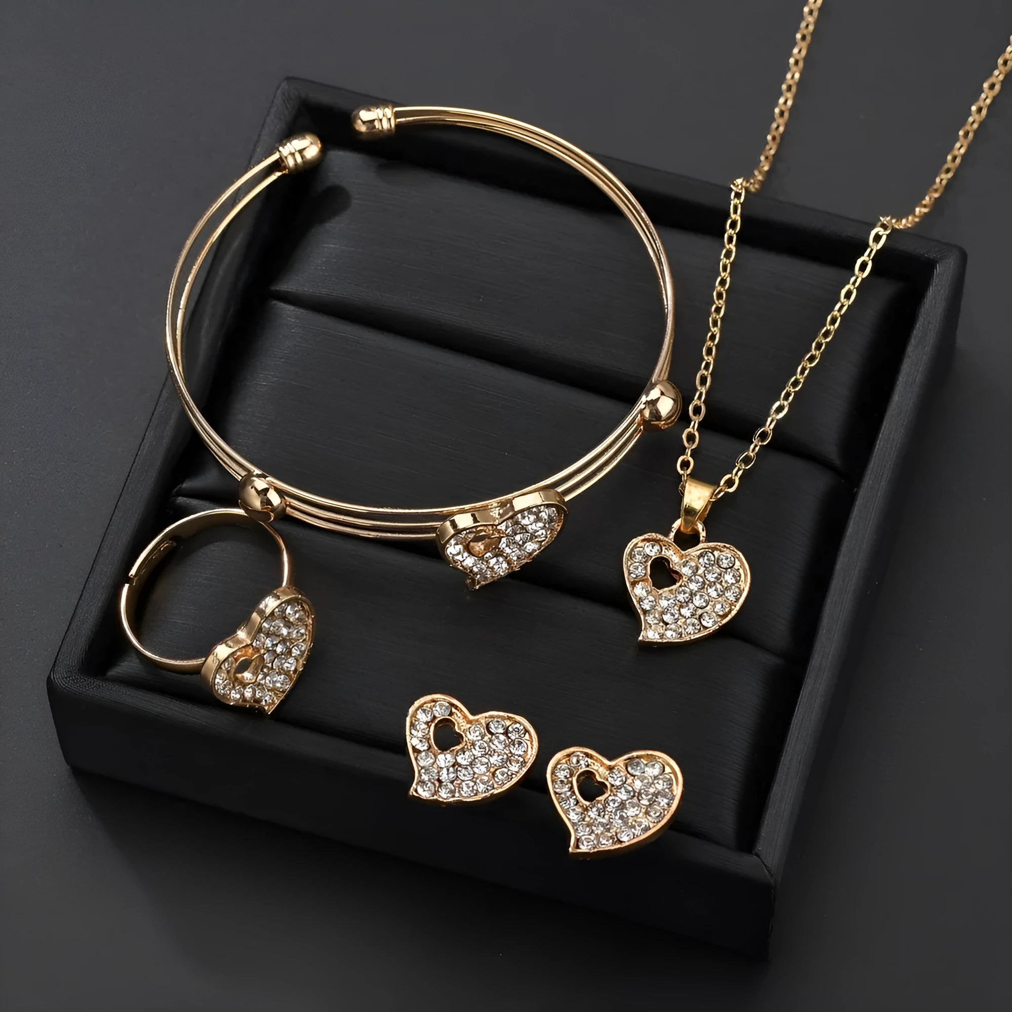 Gold electroplated alloy women's jewellery set with love, water drop, and bell patterned earrings, pendant, and bracelet.