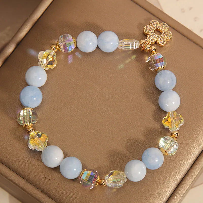 Aquamarine crystal and pearl bracelet with four-leaf clover charm on wrist.