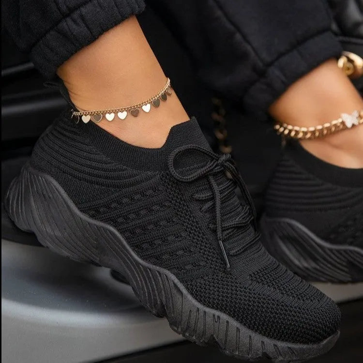 Women's white thick-sole dad sneakers on a plain background, showing the chunky sports shoe design.