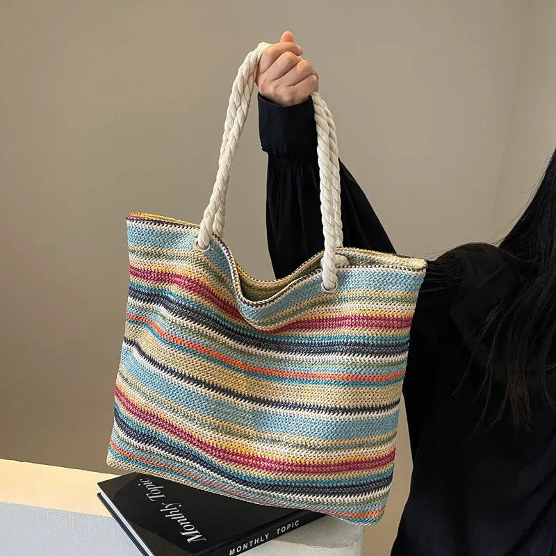 Blue straw woven large capacity shoulder bag with adjustable strap on a neutral background