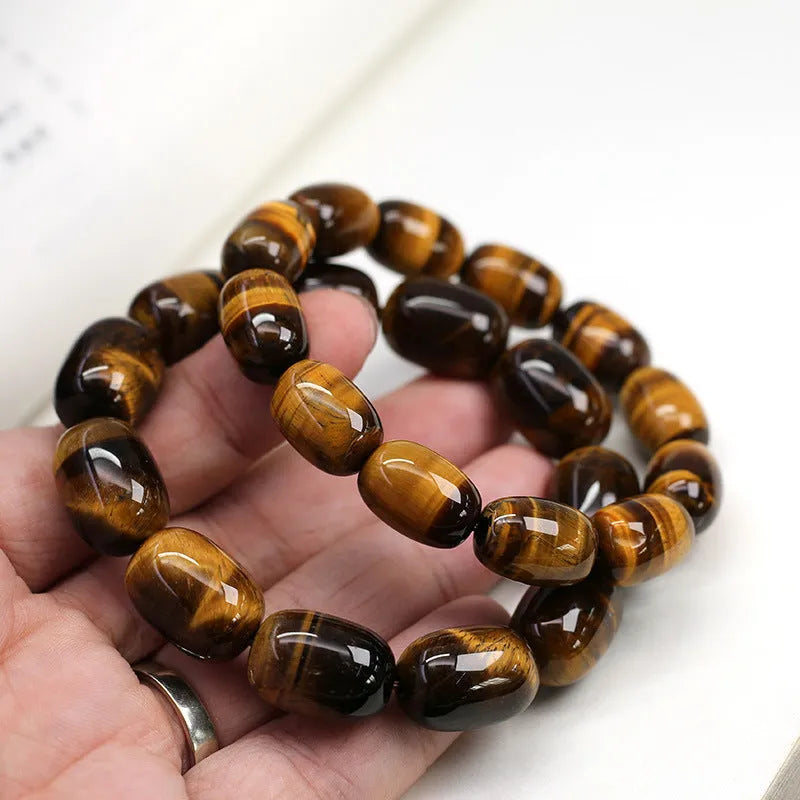 Close-up of a natural yellow Tiger Eye gemstone beaded bracelet with cat's eye effect on a wrist.
