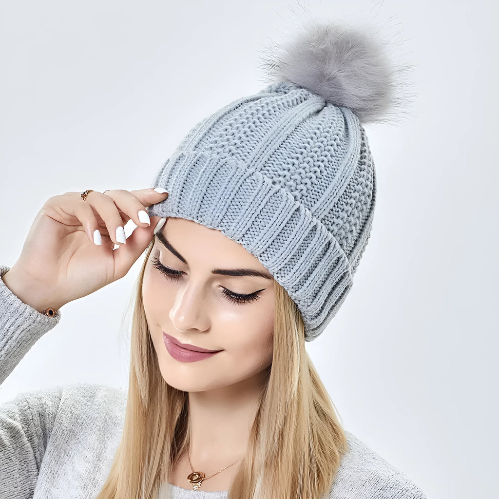 Women's white skull knit beanie with faux fur pom pom, showing satin paisley lining.