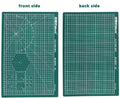 Green A3 self-healing cutting mat with centimetre grid lines on a wooden desk.
