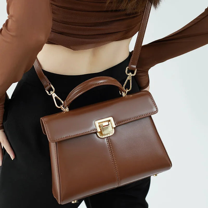 Black leather women's shoulder bag with clasp closure showing internal zippered compartment and adjustable strap