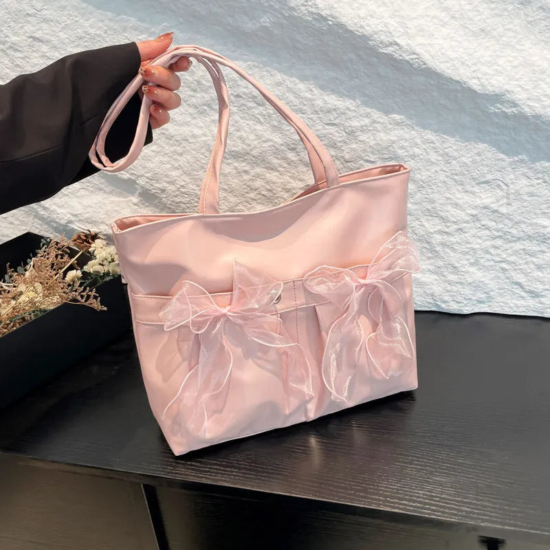 Black PU leather bow tote bag with double shoulder straps, shown with interior zipped pocket.