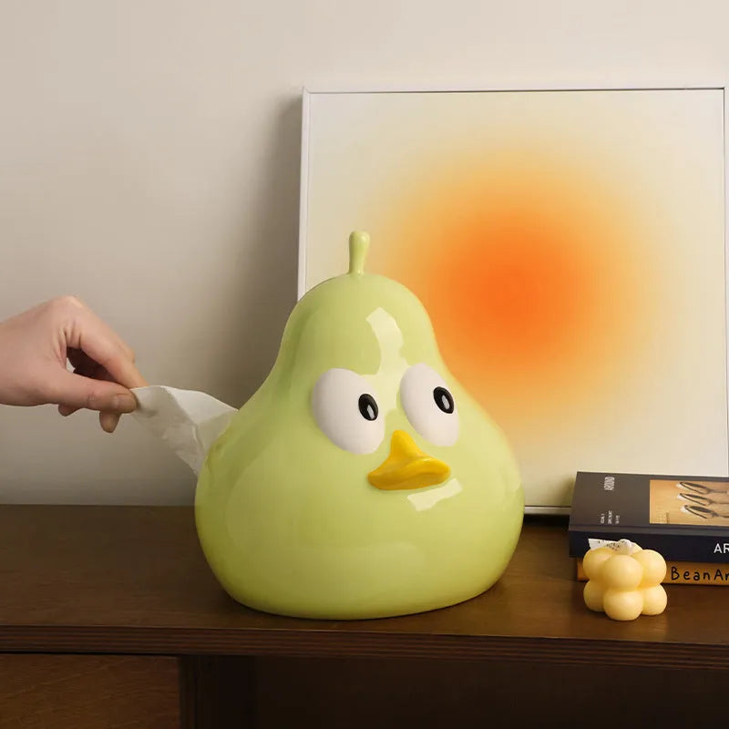 Green ceramic pear tissue box with animal style design on a wooden desktop