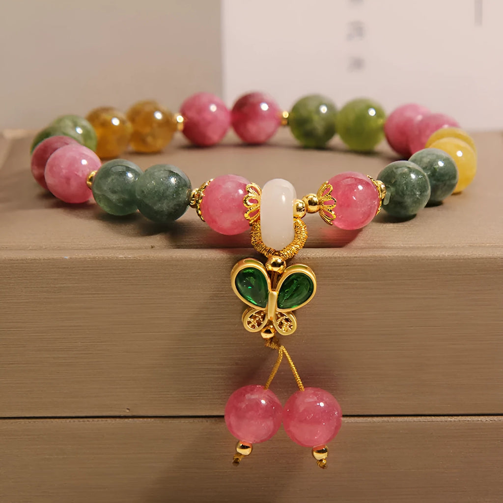 Colourful tourmaline butterfly pendant bracelet with rhinestone details on a woman's wrist.