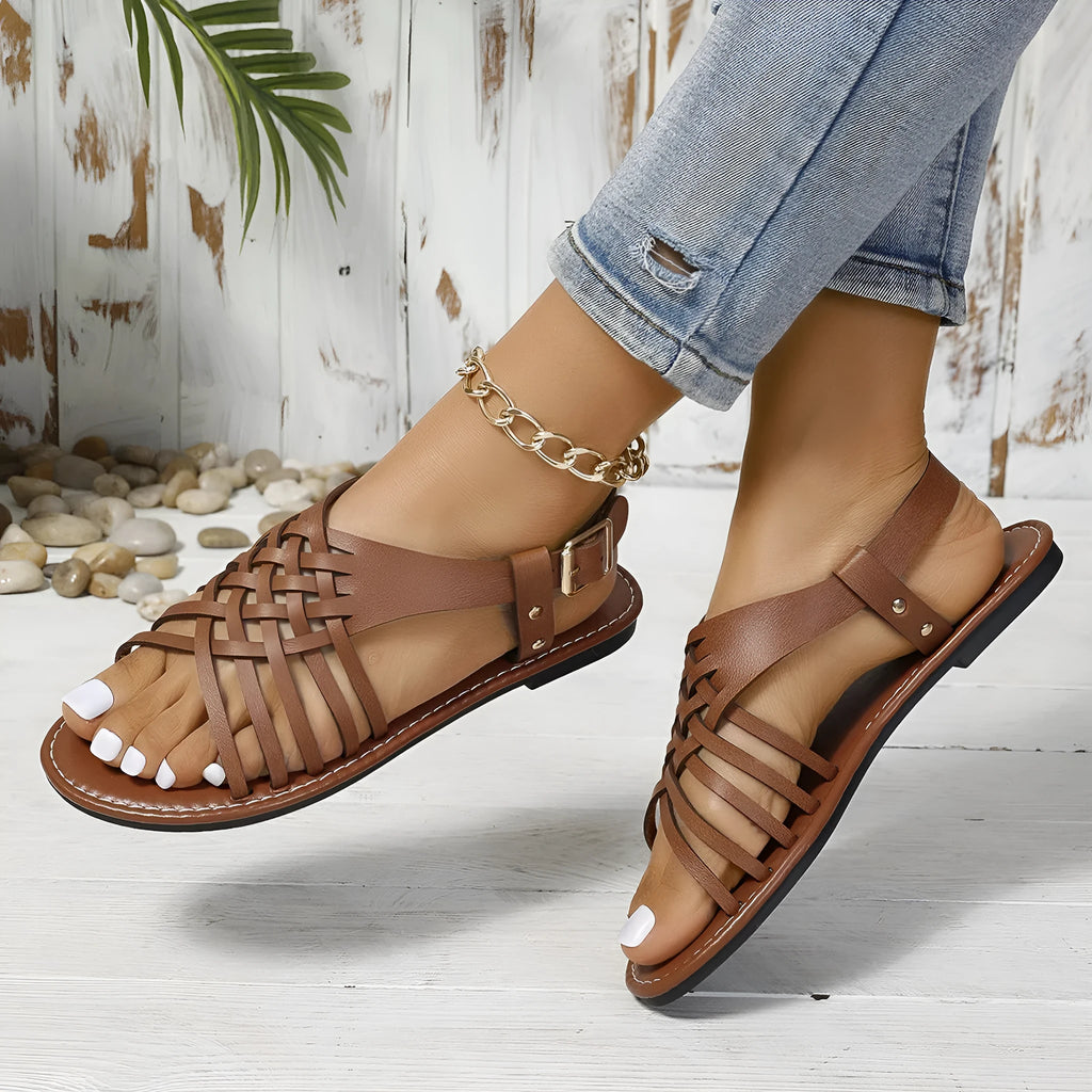 Black Roman style beach slippers with cross straps and flat buckle on open toe design