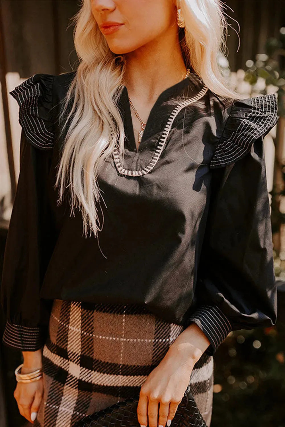Black women's blouse with V-neck, contrast stitching, and three-quarter length ruffle sleeves